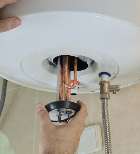 worker fixing a white round water heater attached on a beige wall